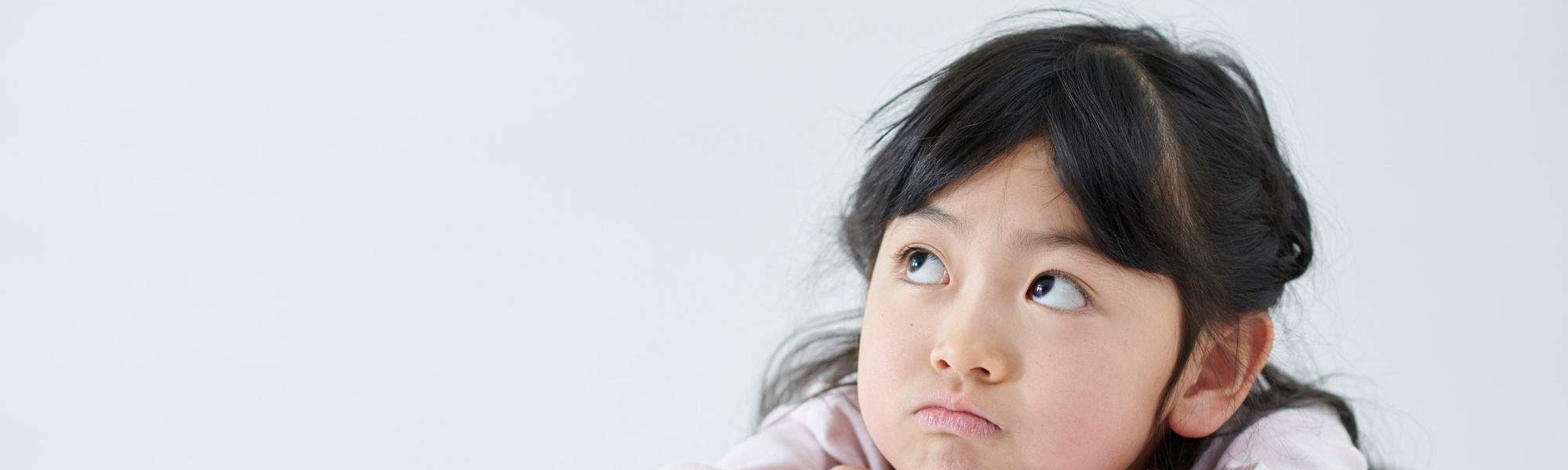 a young girl looks thoughtfully up and to her right.