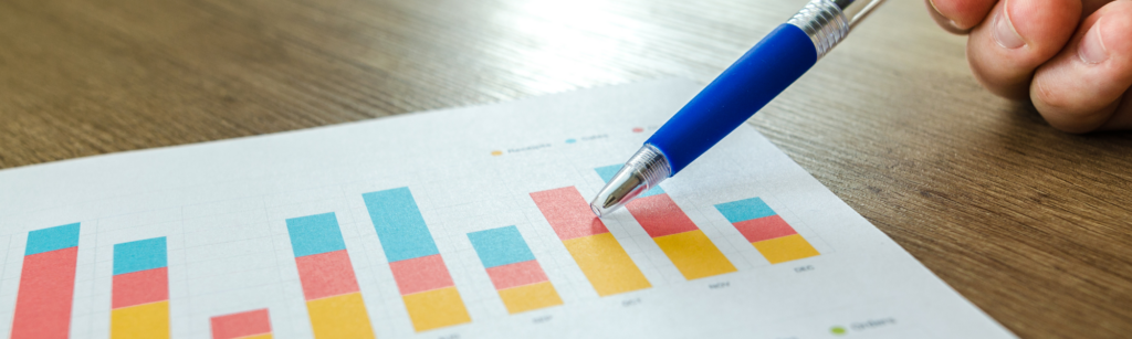 A ballpoint pen rests on top of a bar chart measuring metrics.
